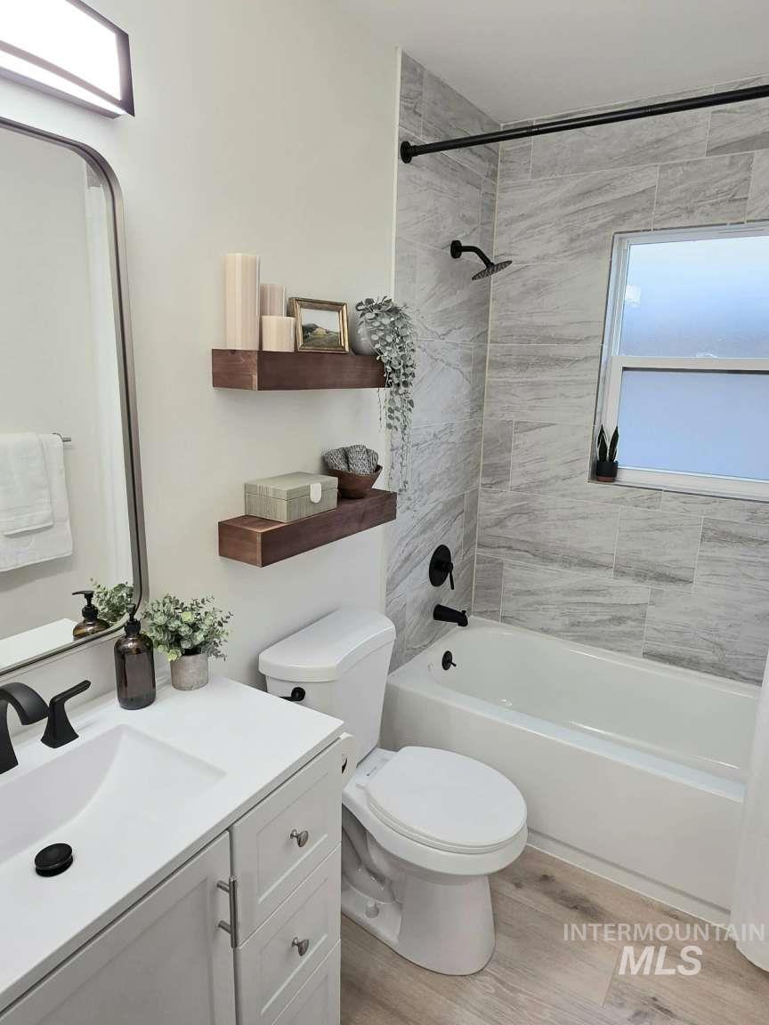 Bathroom with light wood finished floors, vanity, and bathing tub / shower combination