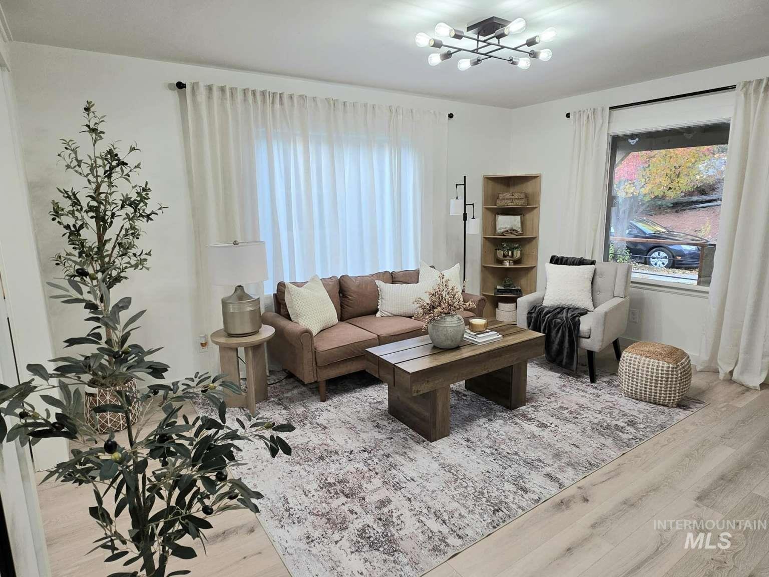 Living area with light wood-type flooring, a chandelier, and plenty of natural light