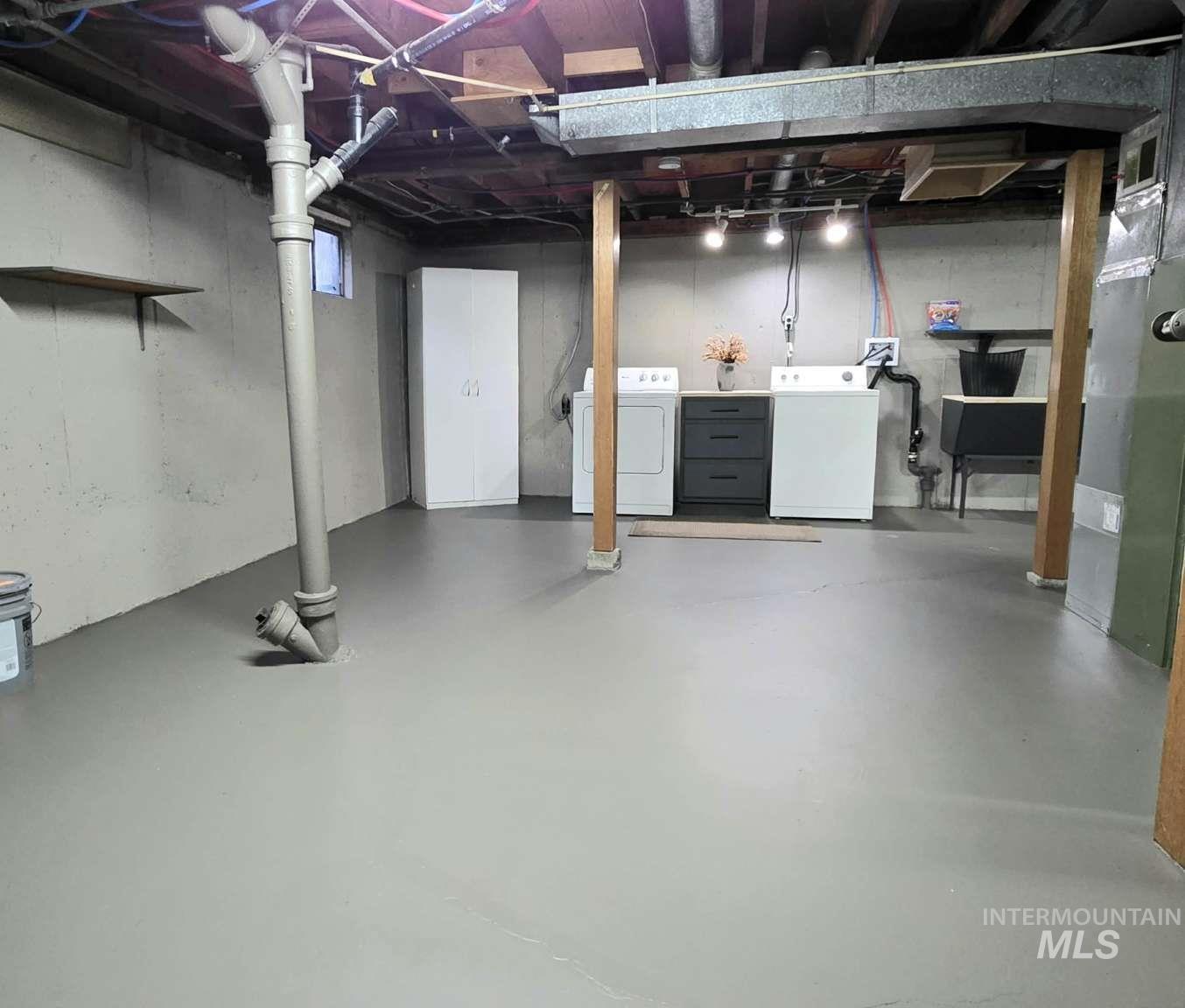 Unfinished basement featuring separate washer and dryer and heating unit