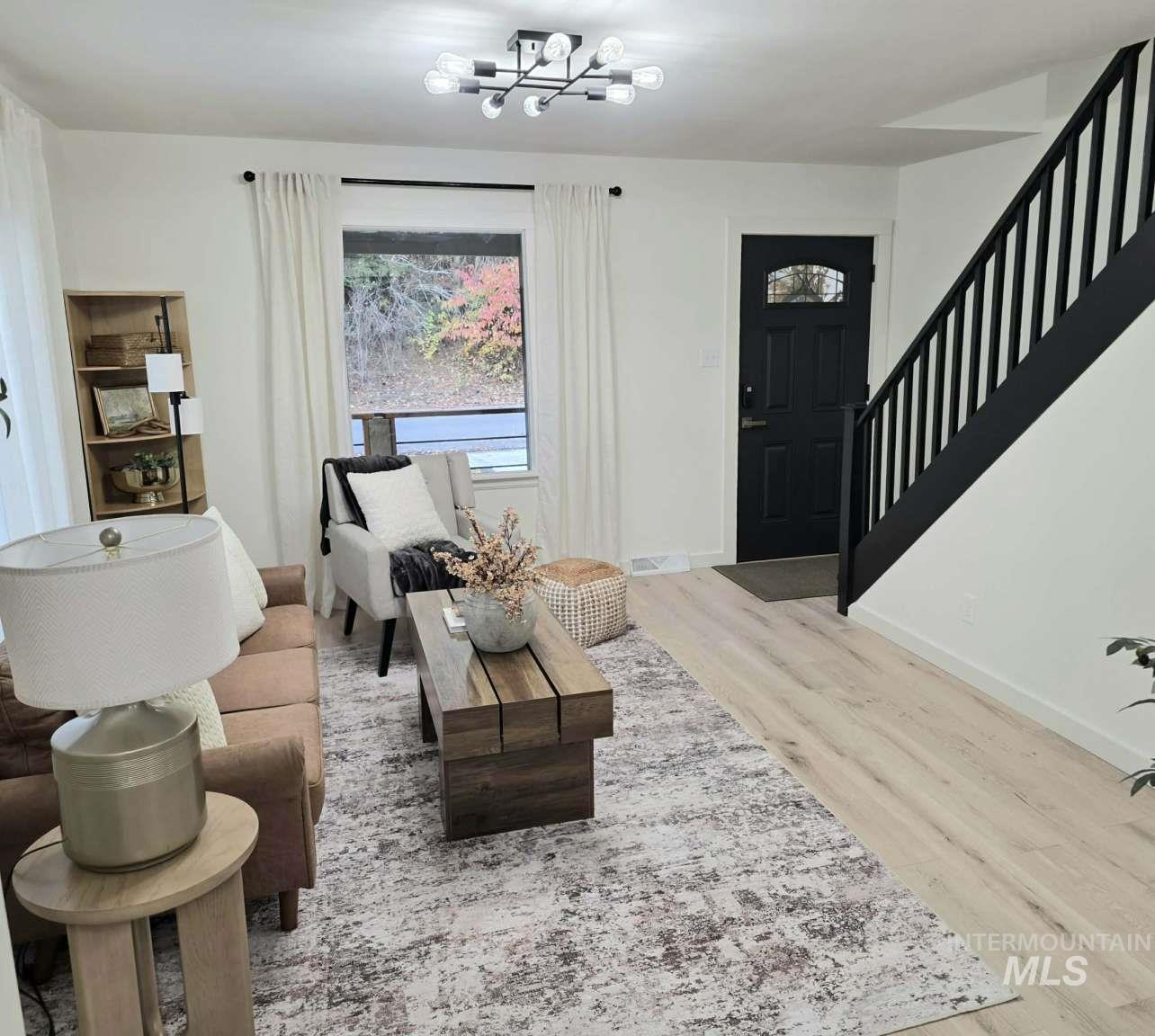 Living area with light wood finished floors, stairs, and a chandelier