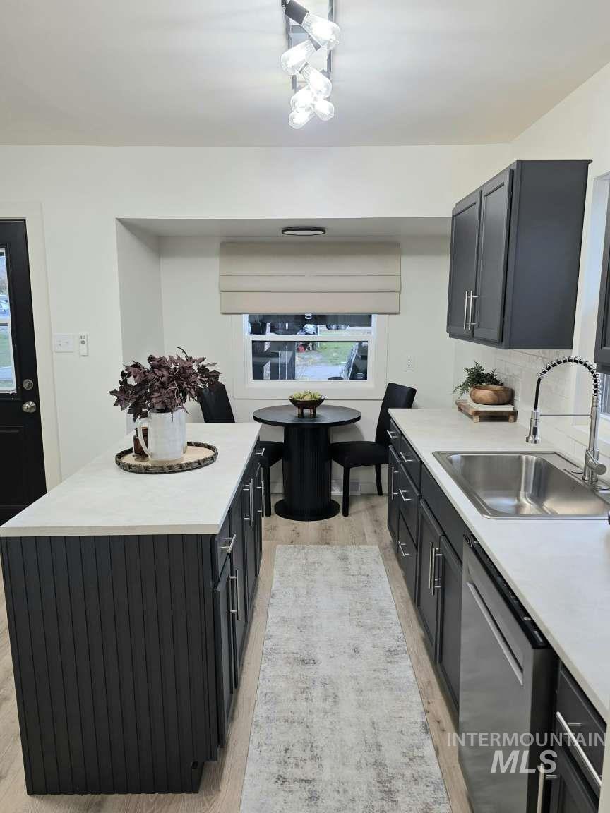 Kitchen featuring light countertops, dark cabinets, and light wood-style floors