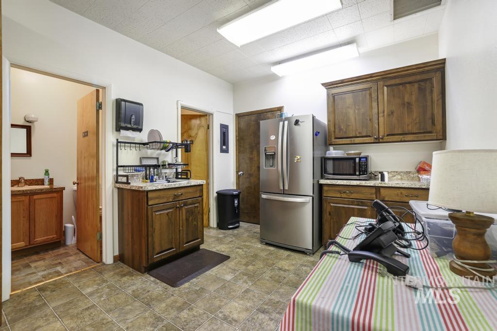 Kitchen featuring stainless steel appliances, dark brown cabinets, stone finish floors, and light stone counters