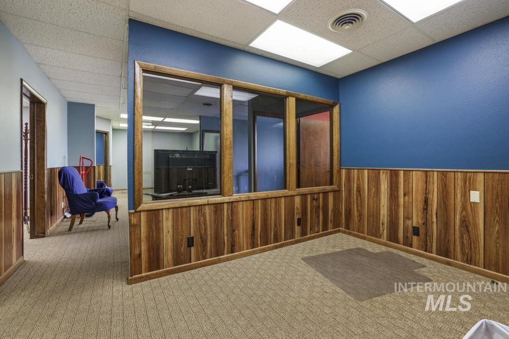 Carpeted spare room with wood walls, wainscoting, and a paneled ceiling