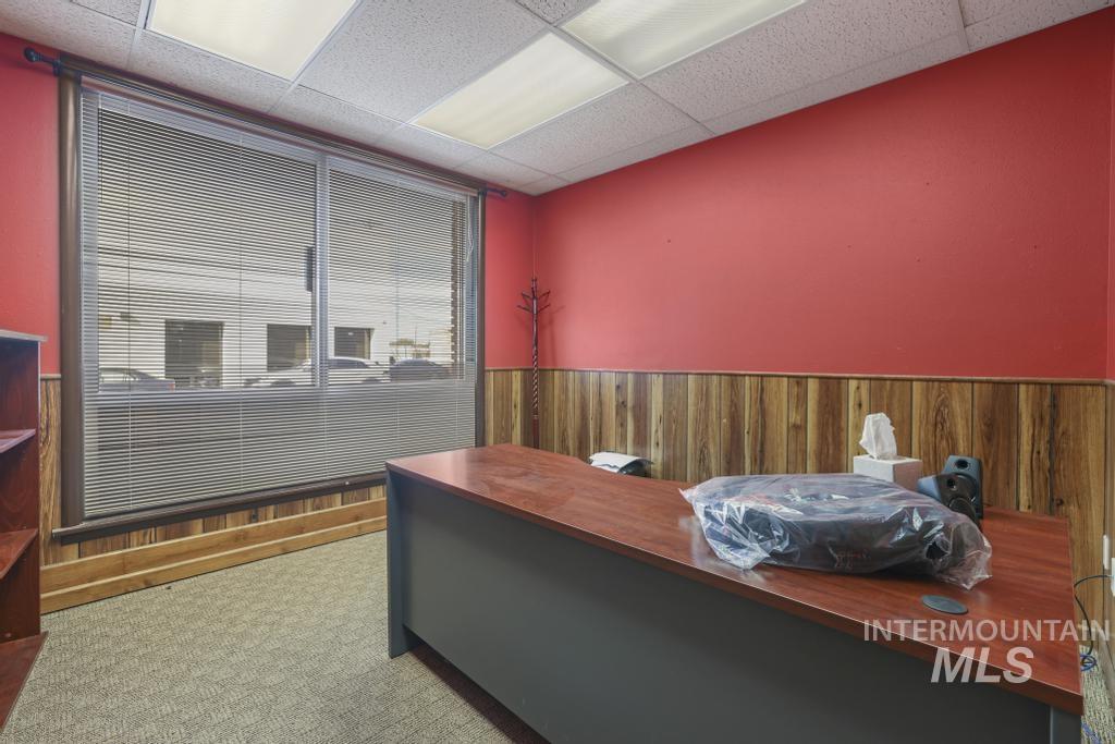 Bedroom featuring wooden walls, a wainscoted wall, a paneled ceiling, and light carpet