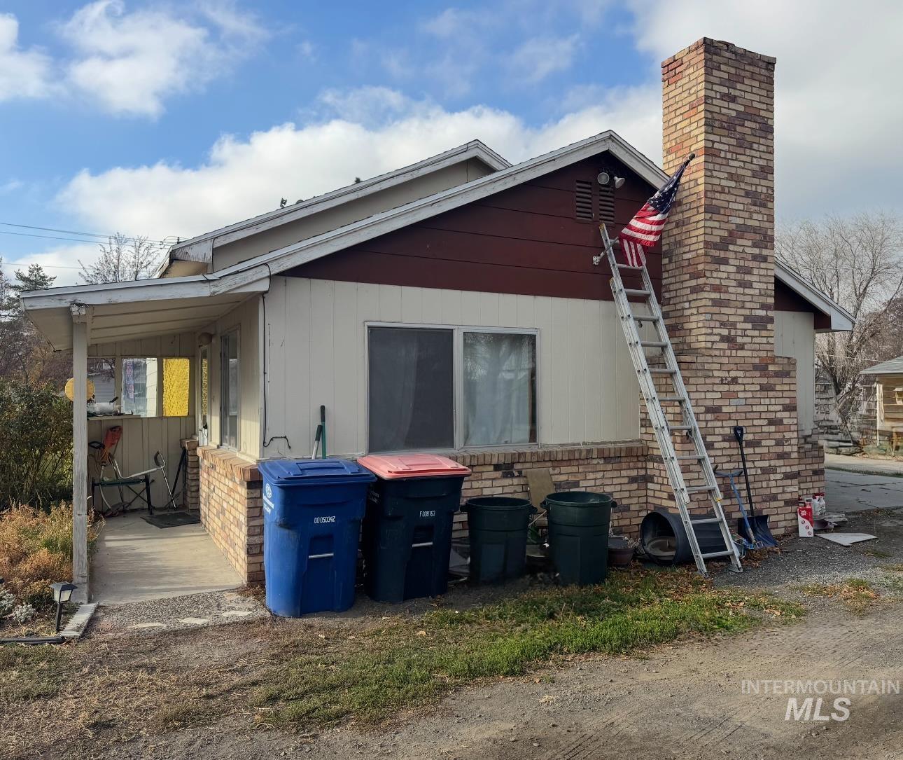 View of property exterior featuring brick siding, a chimney, and a patio