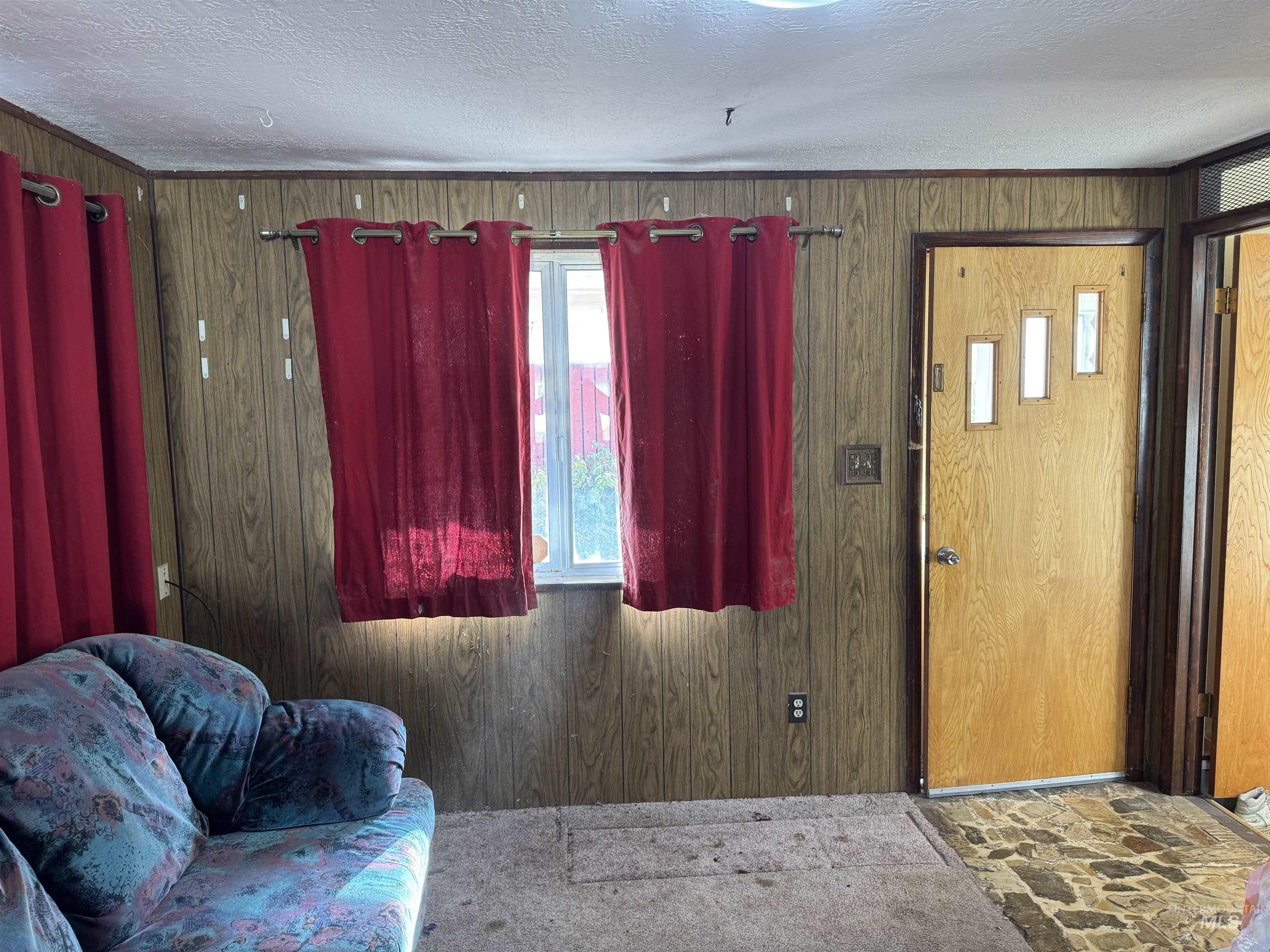 Entrance foyer with wooden walls, a textured ceiling, and stone finish flooring