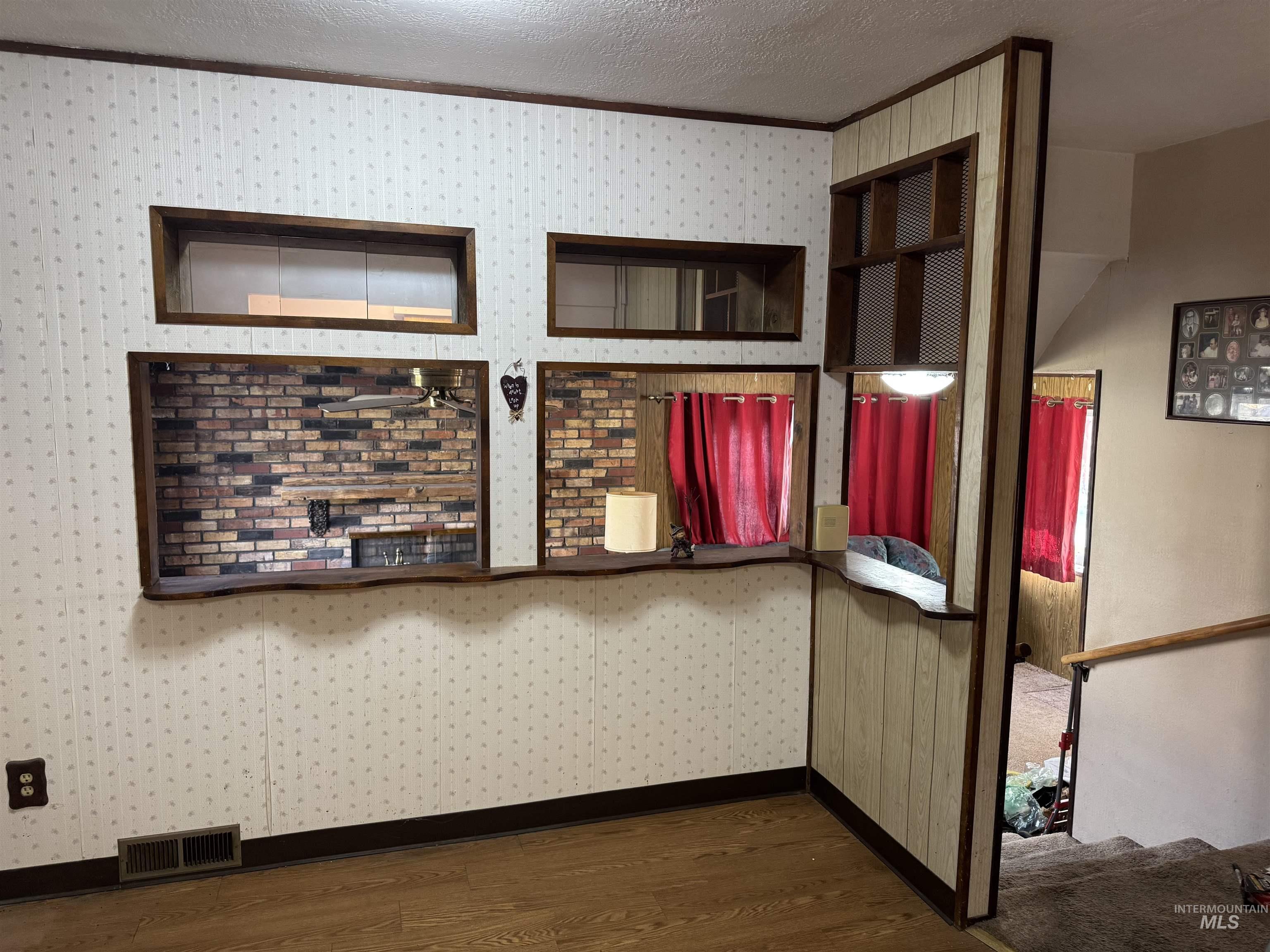 Detailed view of wood finished floors, a textured ceiling, and crown molding