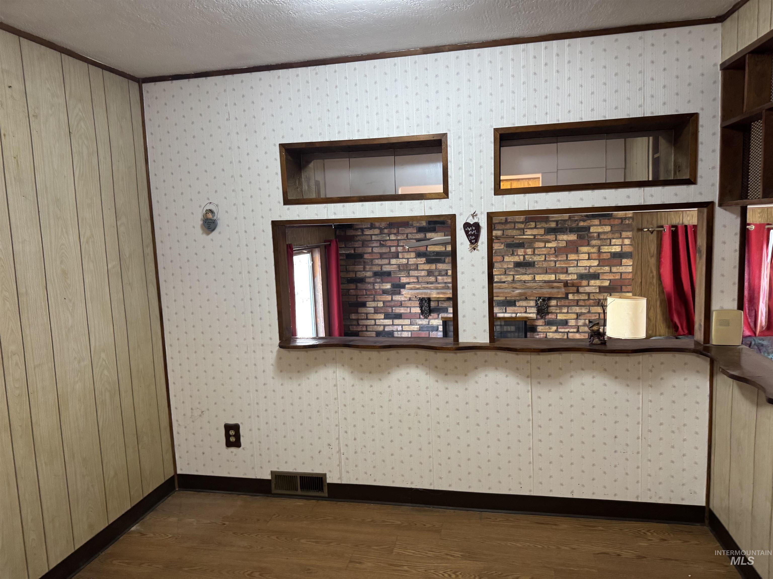Unfurnished room featuring dark wood-style floors, ornamental molding, and a textured ceiling