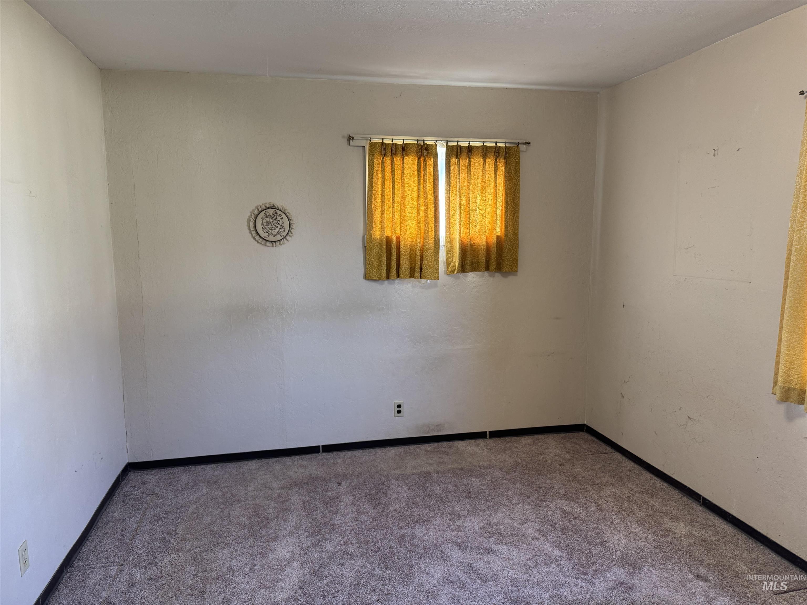 Carpeted empty room featuring baseboards