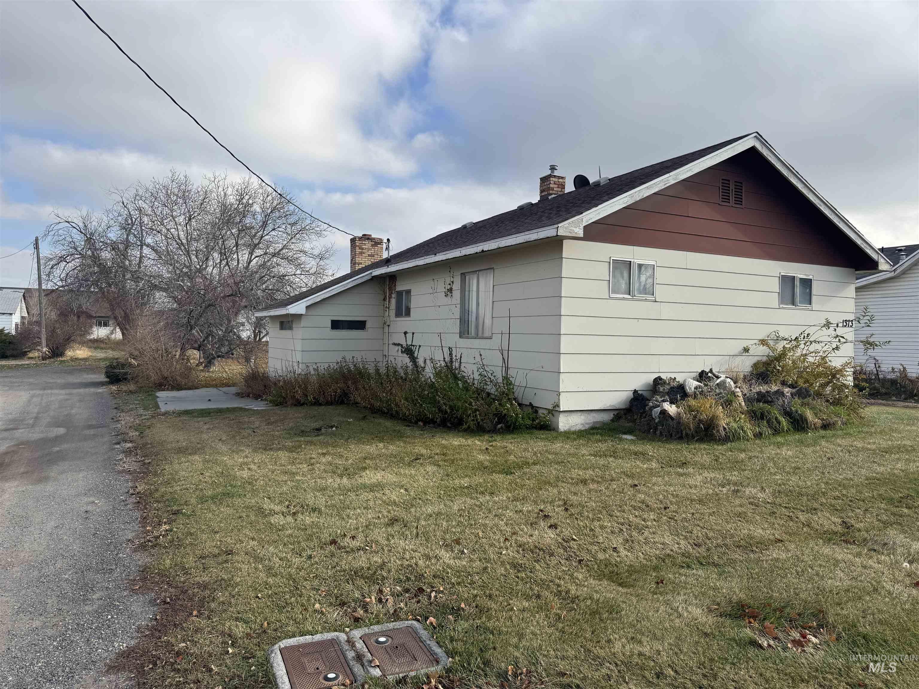 View of side of home with a chimney and a lawn