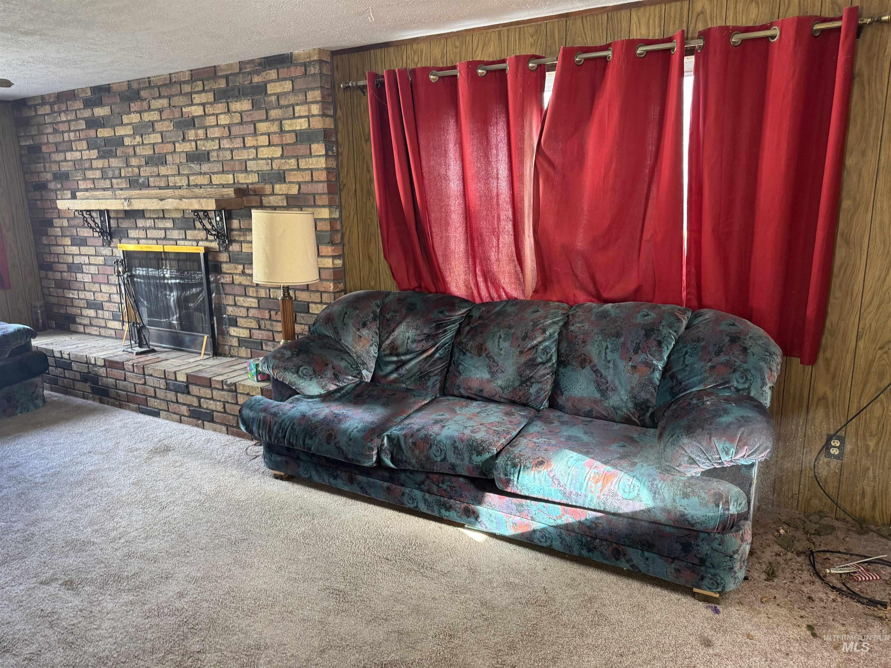 Living room featuring carpet floors, a brick fireplace, and a textured ceiling