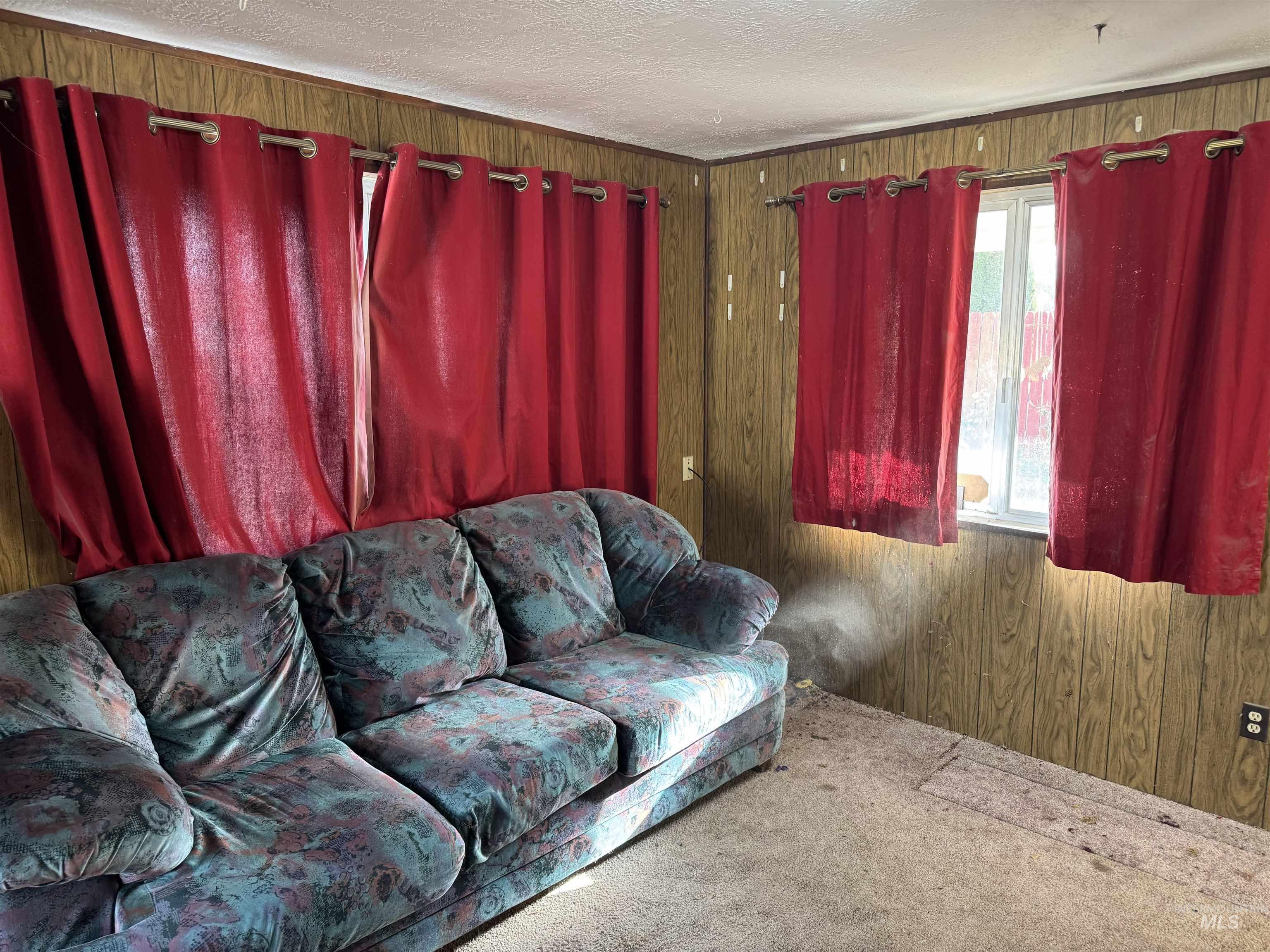 Carpeted living area featuring wooden walls and a textured ceiling