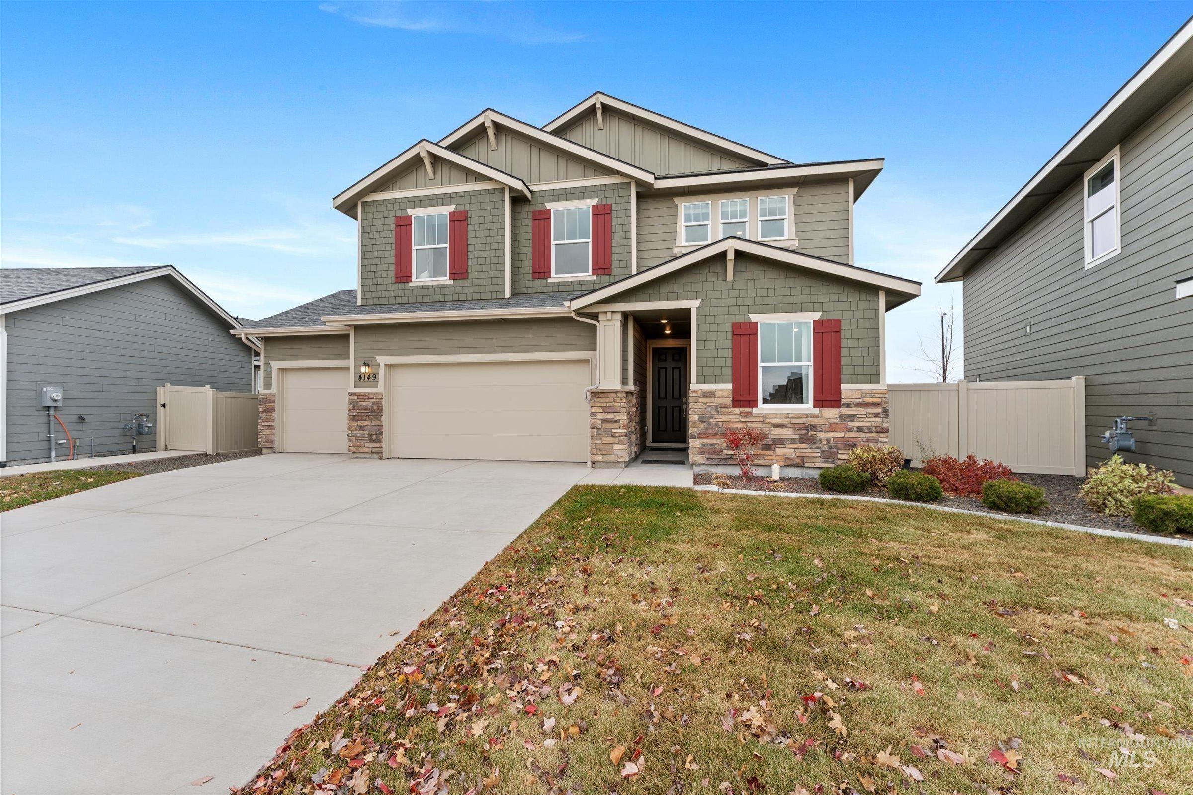 Craftsman house with stone siding, a garage, board and batten siding, and driveway