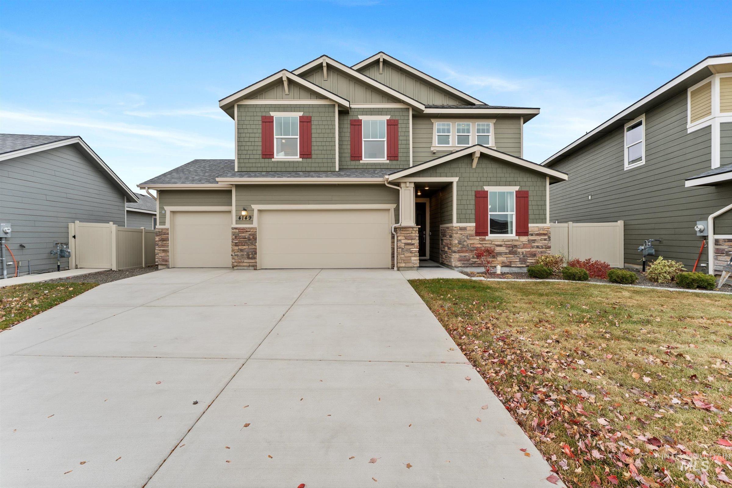 Craftsman inspired home featuring stone siding, an attached garage, driveway, and board and batten siding