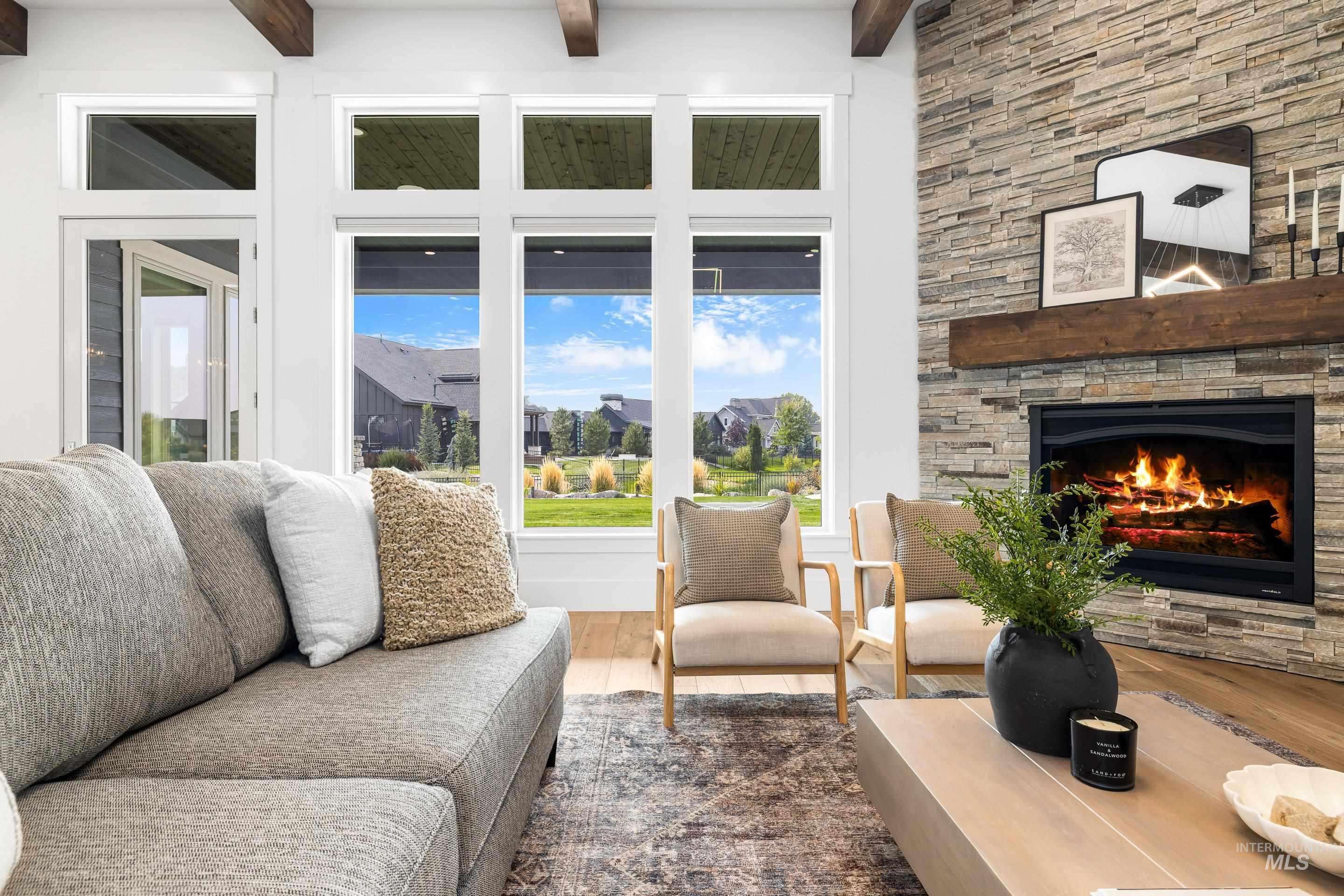 Living area with dark wood-type flooring, beam ceiling, a fireplace, and a high ceiling