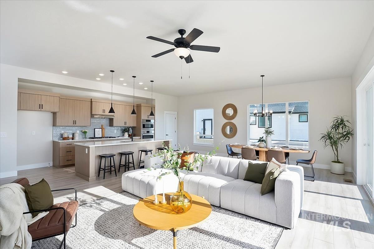 Living room with recessed lighting, light wood finished floors, a chandelier, and ceiling fan