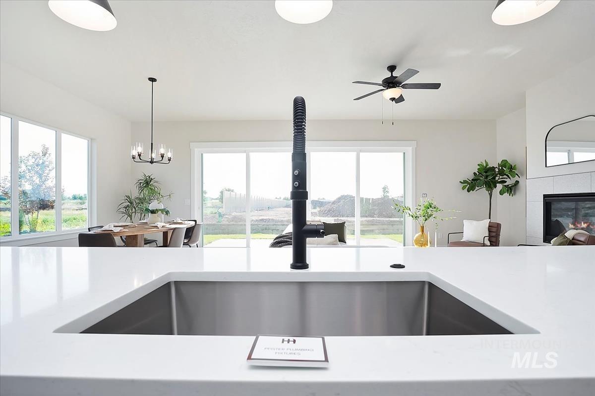 Kitchen featuring light stone countertops, decorative light fixtures, a tile fireplace, and open floor plan