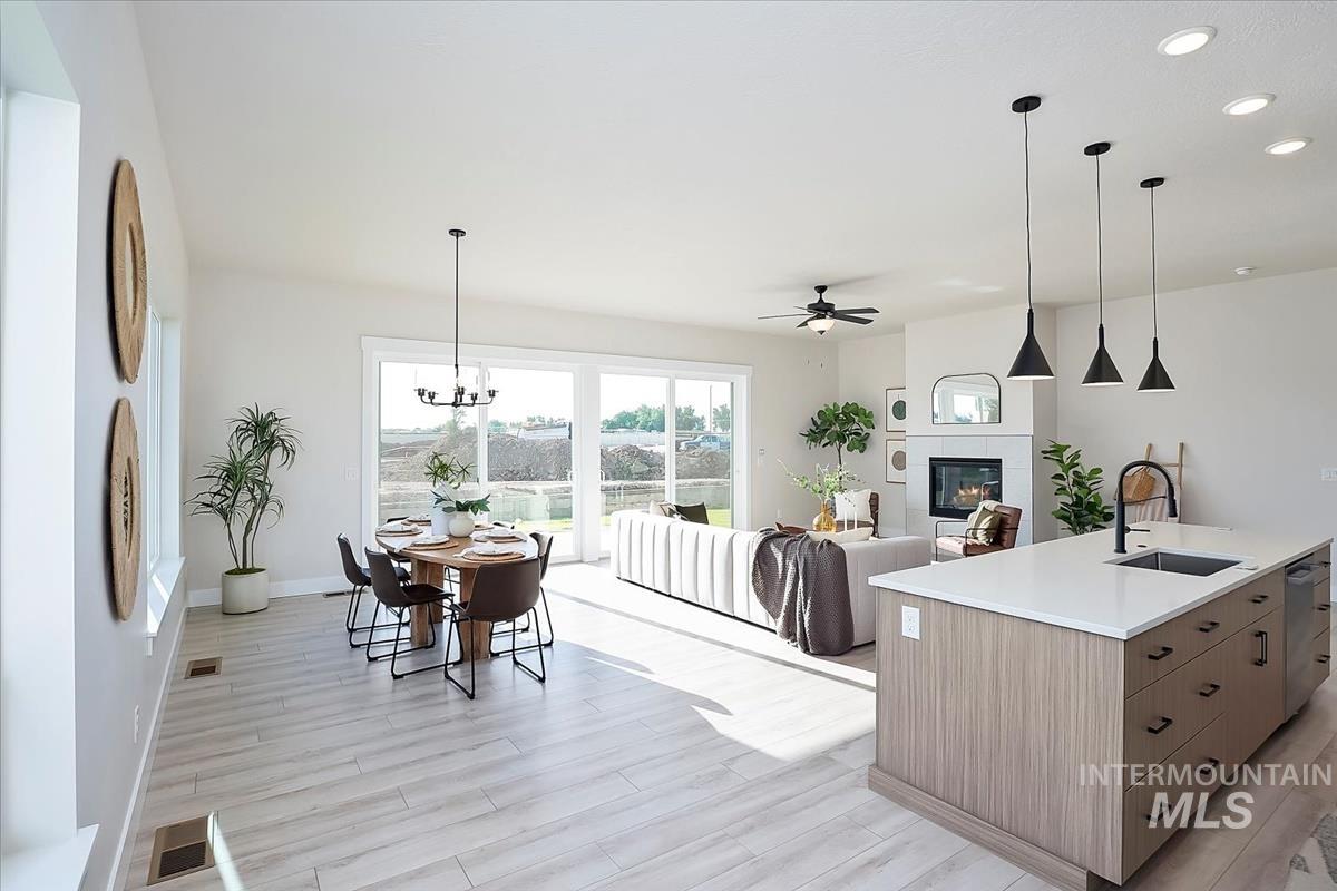 Kitchen featuring pendant lighting, a ceiling fan, a glass covered fireplace, recessed lighting, and light wood-type flooring