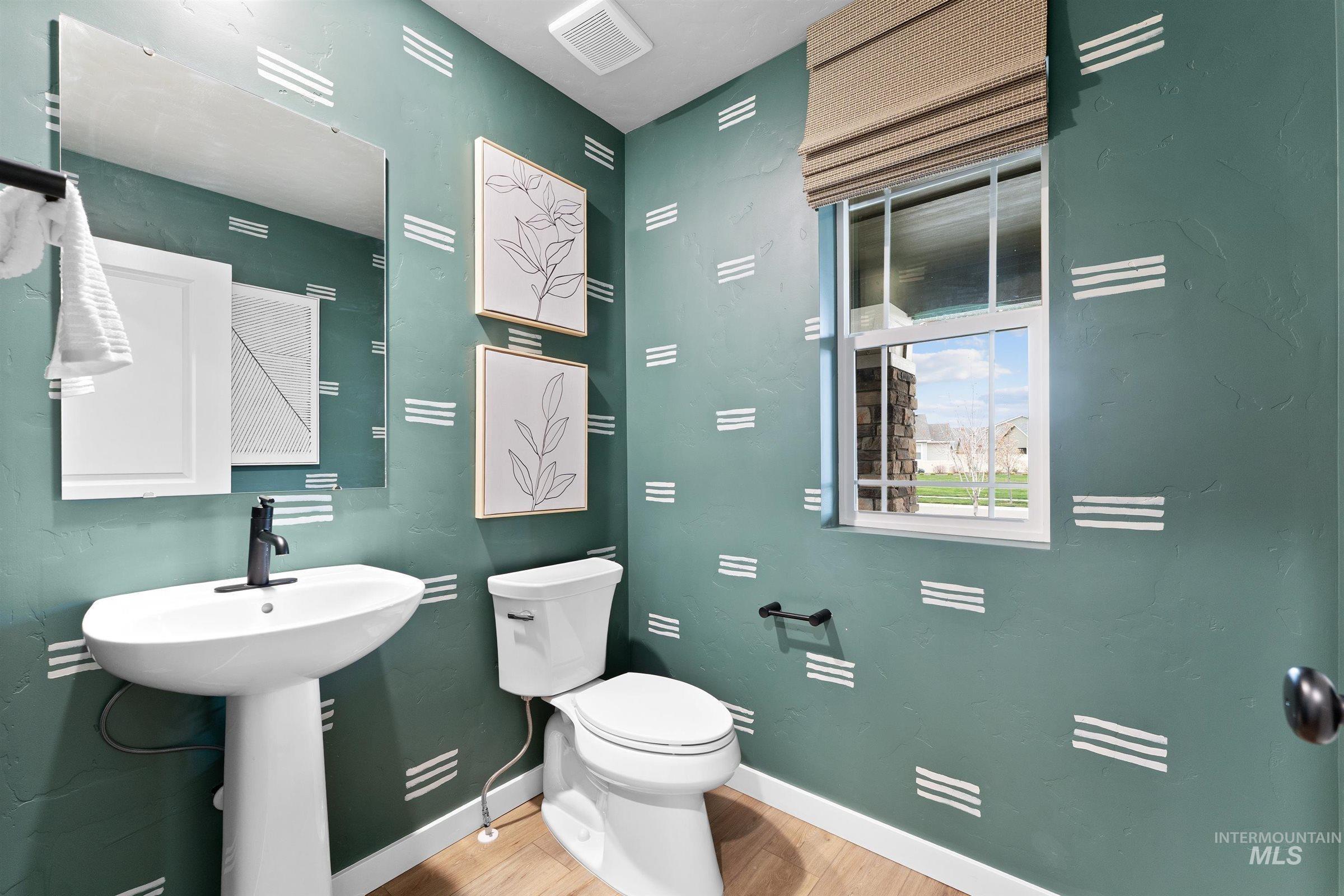 Half bath with light wood-style flooring and toilet