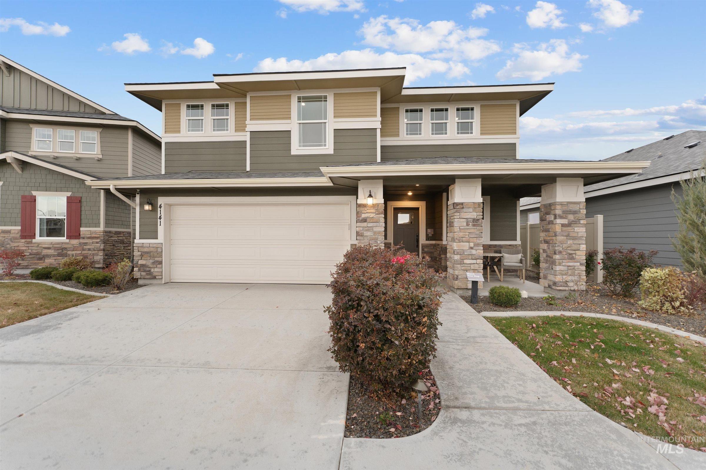 Prairie-style house with stone siding, concrete driveway, a porch, and an attached garage