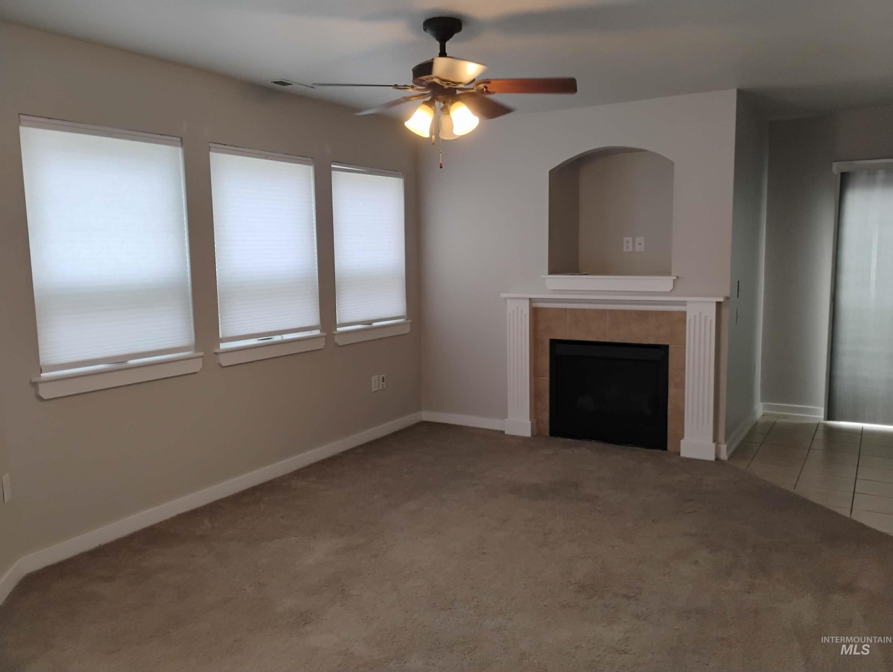Unfurnished living room with light carpet, a fireplace, and ceiling fan