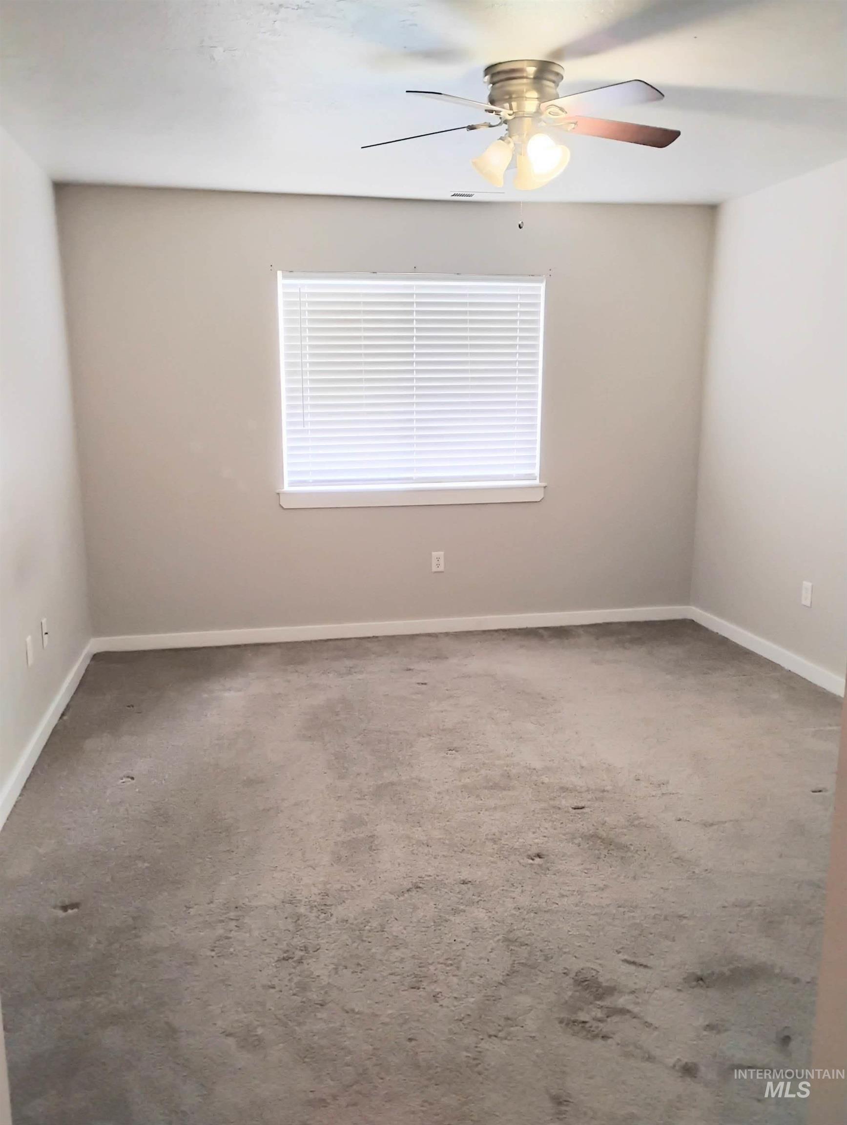 Empty room with light carpet, a ceiling fan, and plenty of natural light