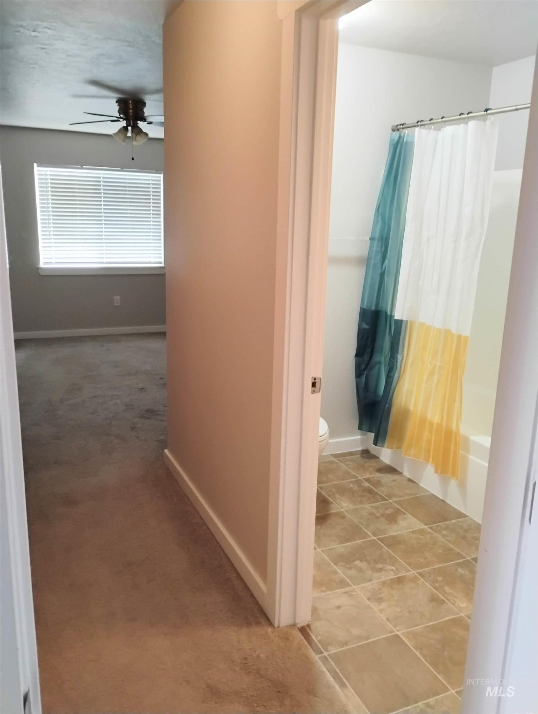 Hallway with light colored carpet and light tile patterned flooring
