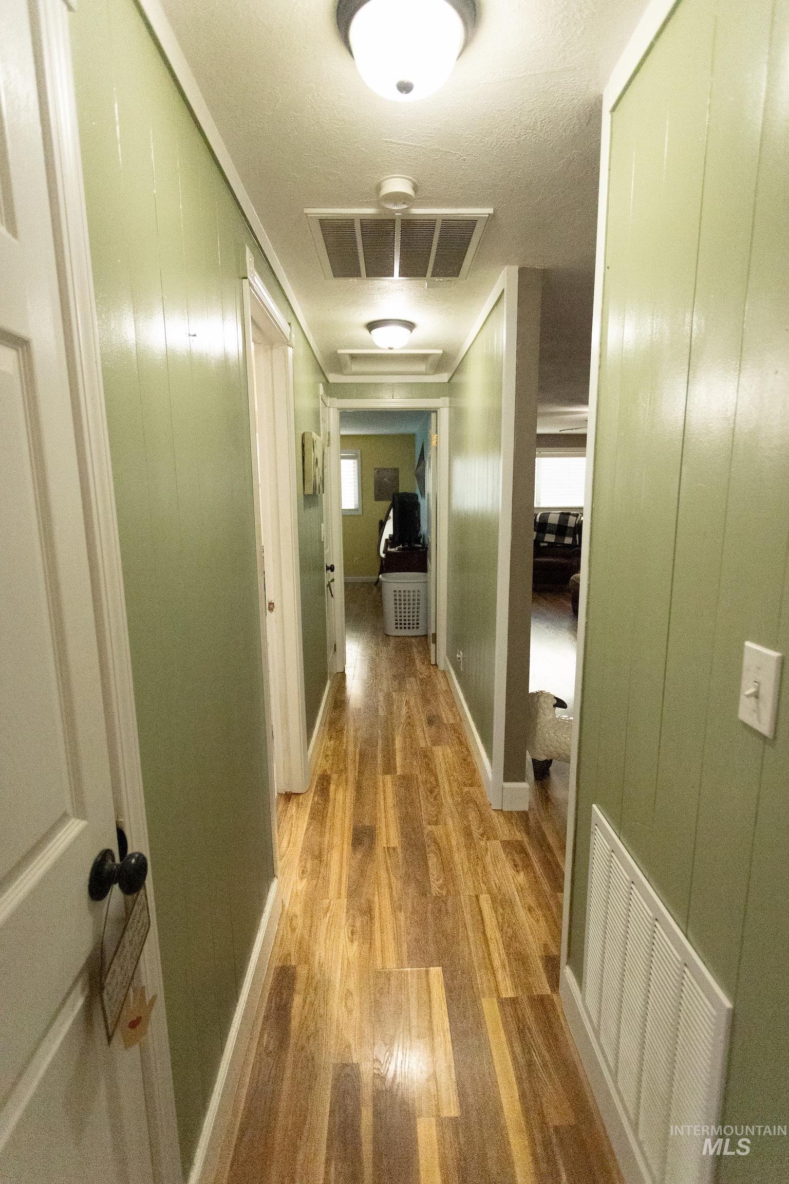 Hall featuring light wood-type flooring and wood walls