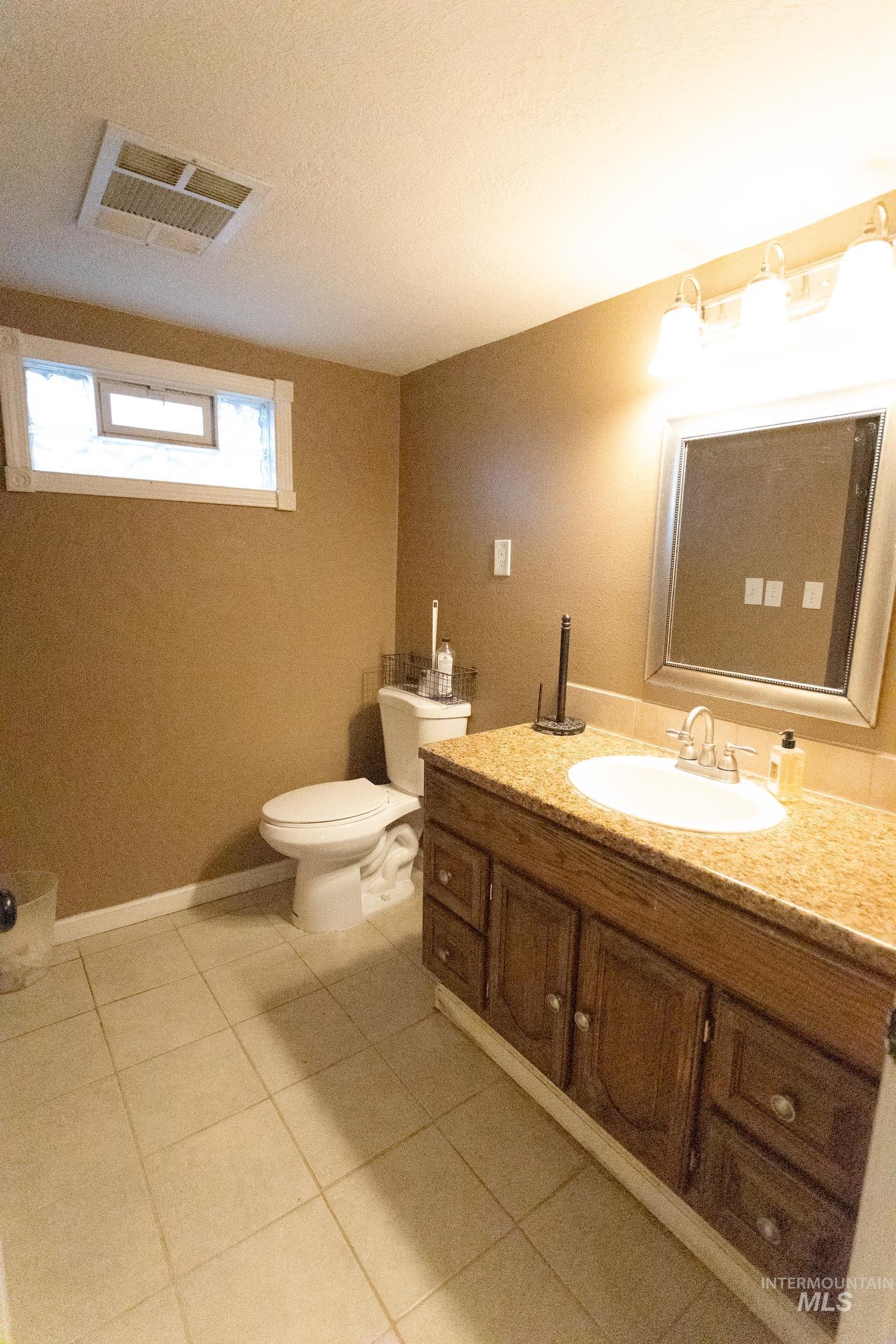 Half bathroom featuring vanity, light tile patterned floors, and a textured ceiling
