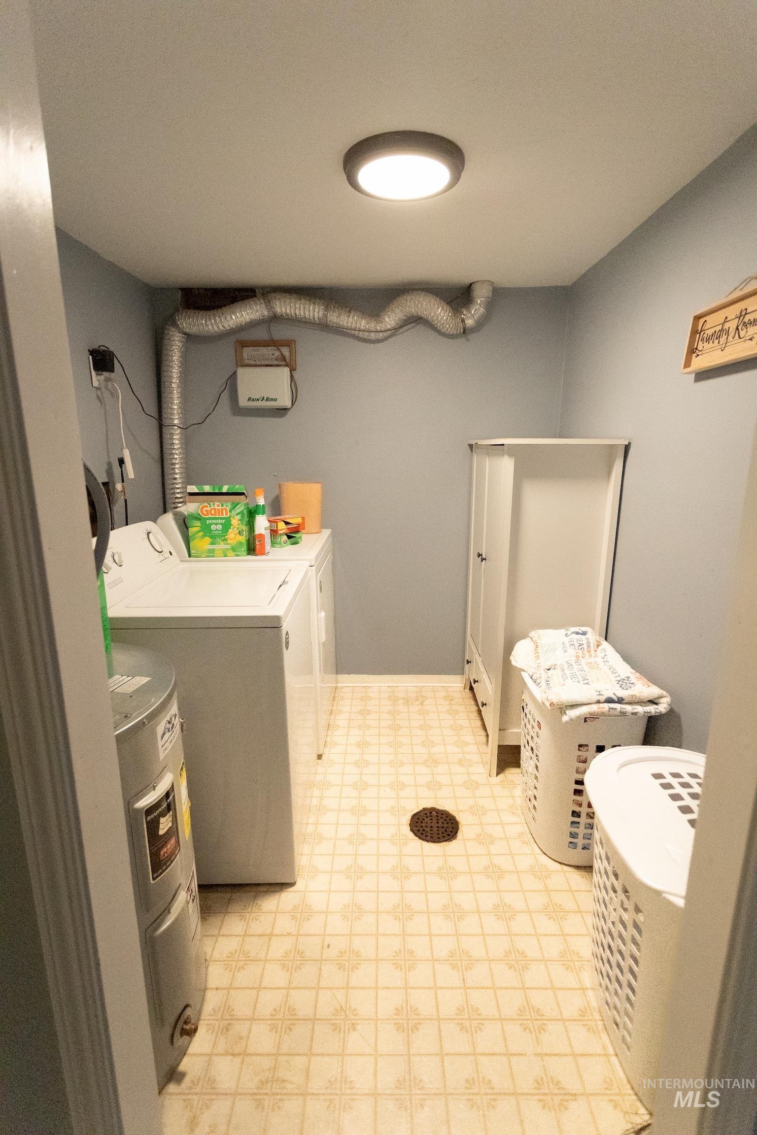 Laundry area featuring washer and clothes dryer, light floors, and water heater