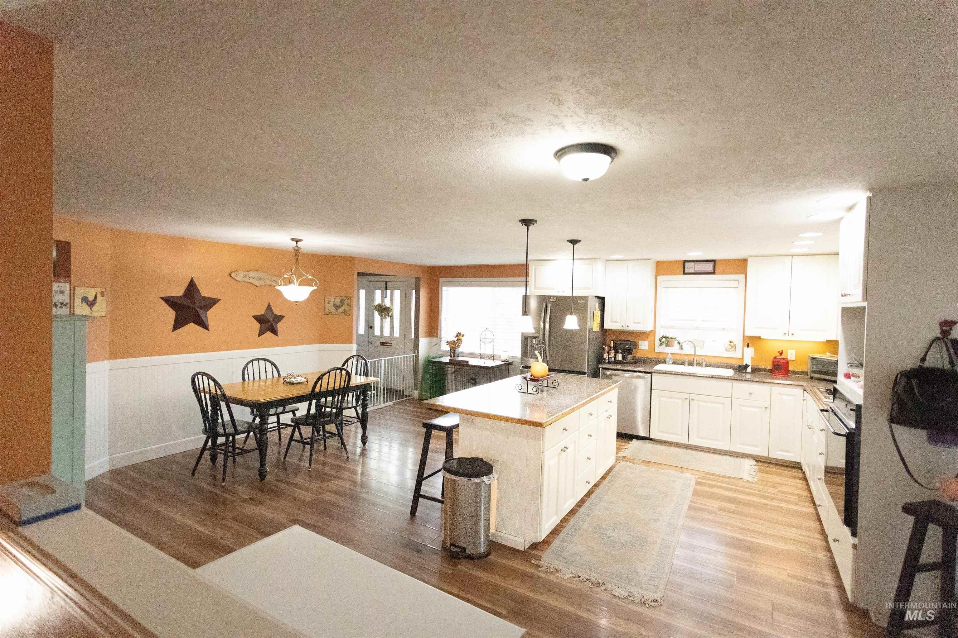 Kitchen with white cabinets, a breakfast bar area, dark wood-type flooring, a center island, and appliances with stainless steel finishes