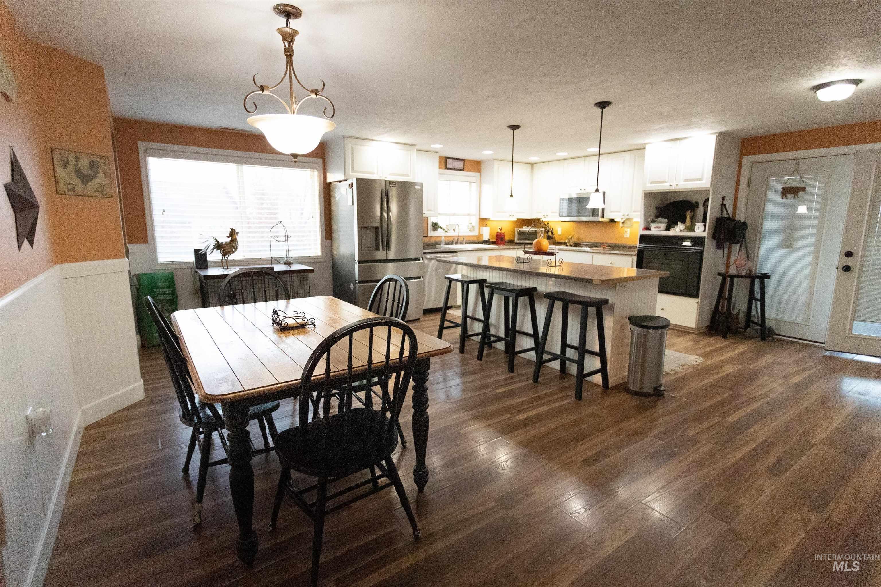 Dining space featuring dark wood finished floors, wainscoting, and a textured ceiling