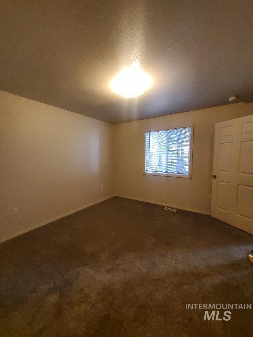 Unfurnished room with dark carpet and baseboards