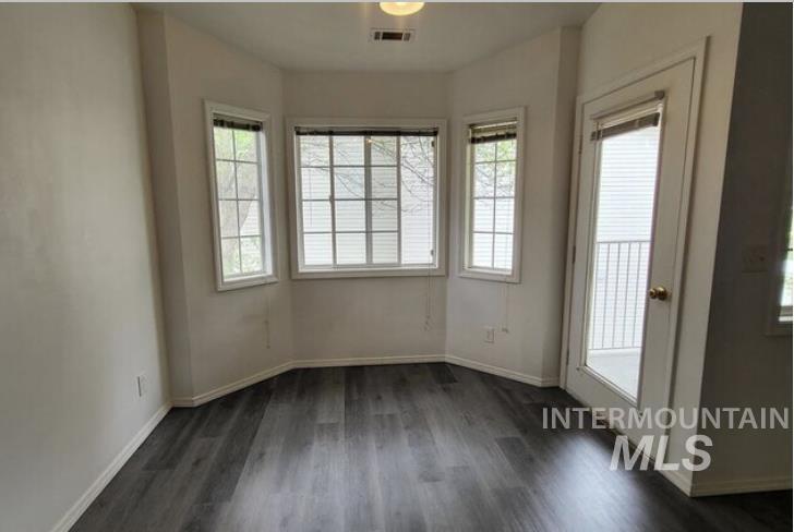Spare room with dark wood-style flooring and baseboards