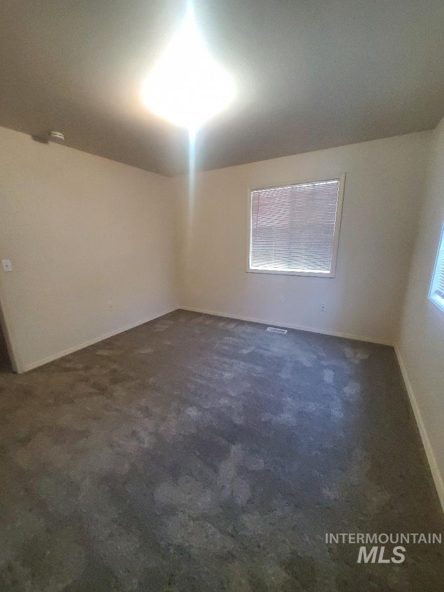 Spare room with dark colored carpet and baseboards