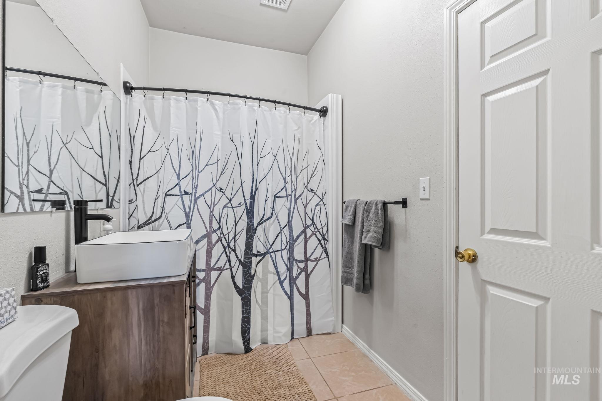 Bathroom with vanity, light tile patterned floors, and a shower with shower curtain