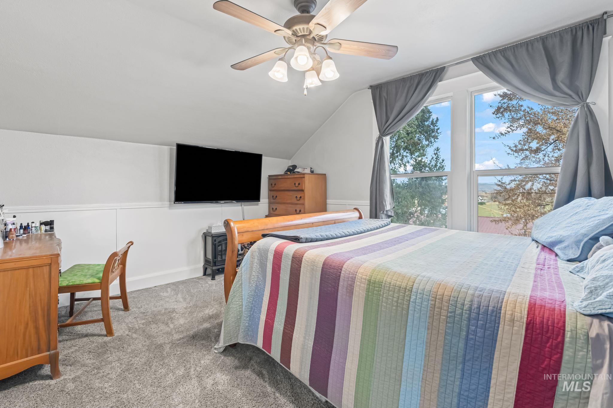Carpeted bedroom with vaulted ceiling and a ceiling fan