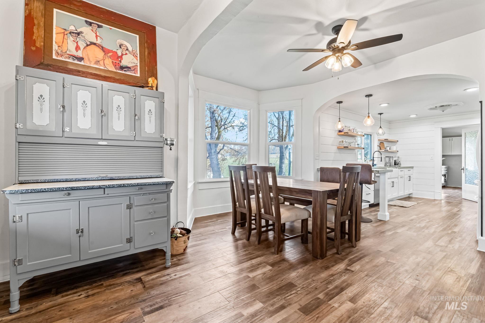 Dining space with arched walkways, light wood-style floors, and a ceiling fan