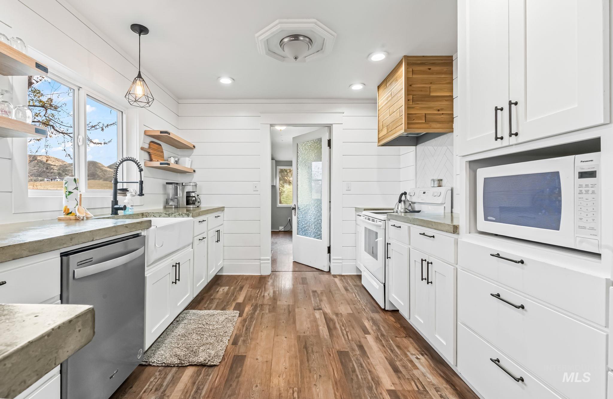 Kitchen featuring open shelves, white cabinets, white appliances, dark wood-style floors, and light stone countertops