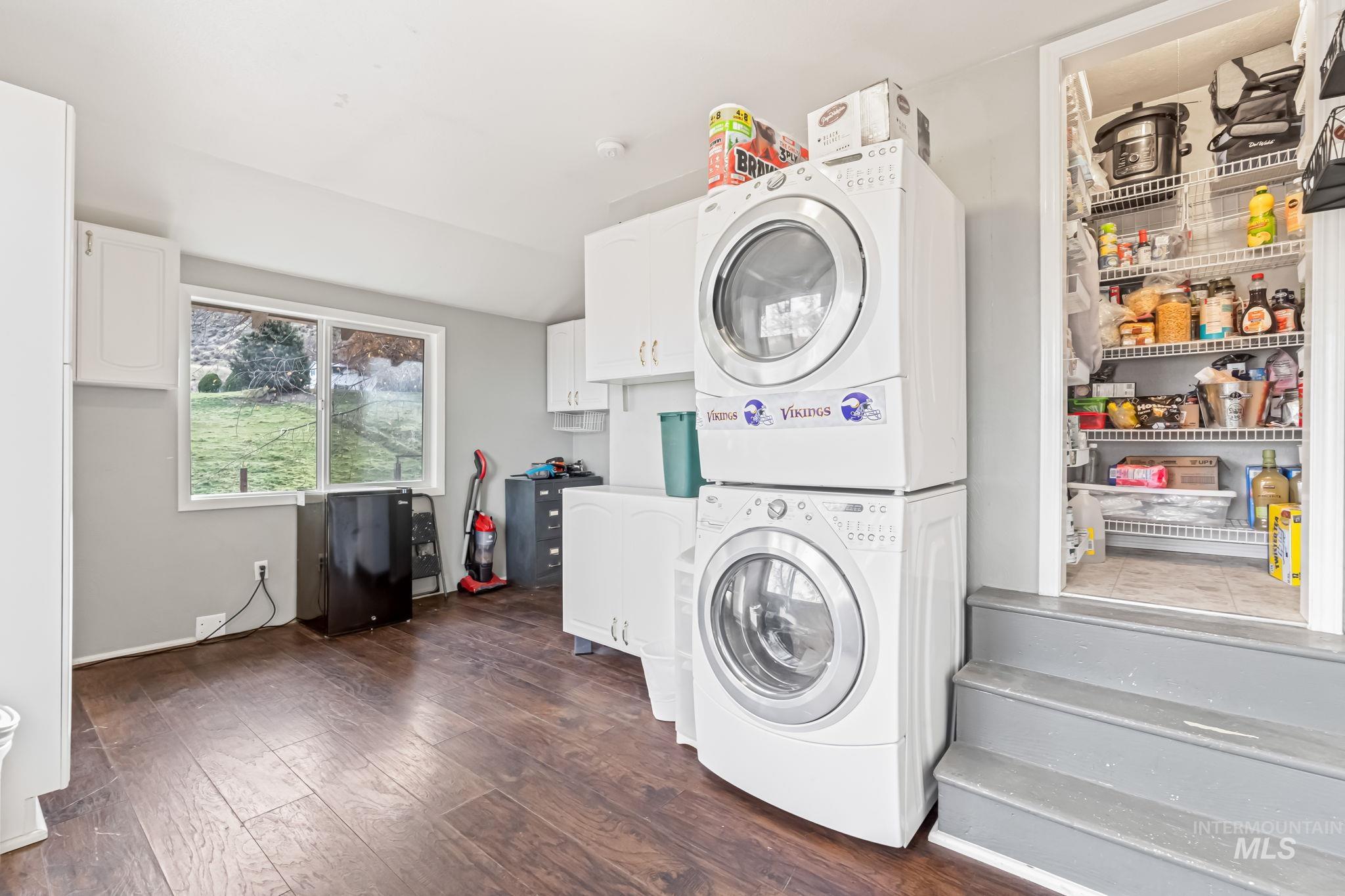 Washroom with dark wood finished floors and stacked washer and clothes dryer