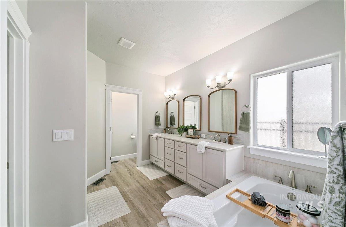 Bathroom with double vanity, a garden tub, and wood finished floors
