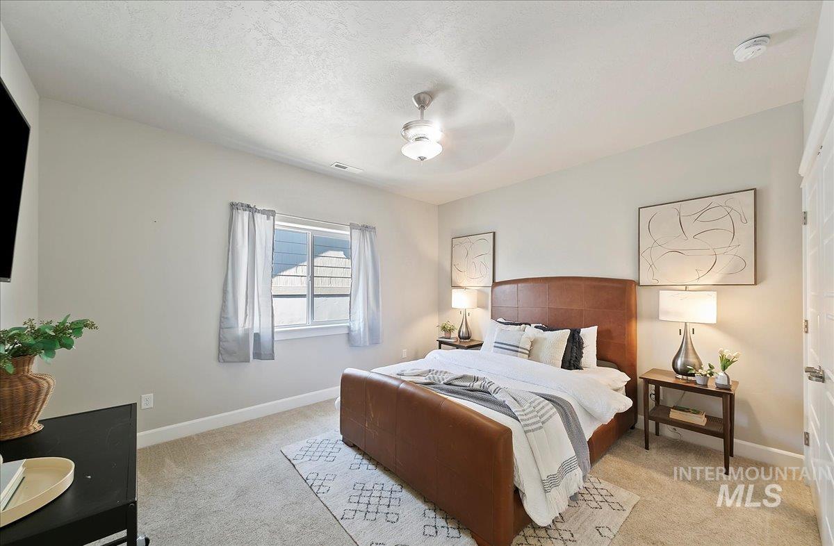 Bedroom featuring light colored carpet, a textured ceiling, and ceiling fan
