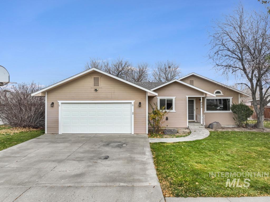 Ranch-style home featuring a front yard, driveway, and a garage