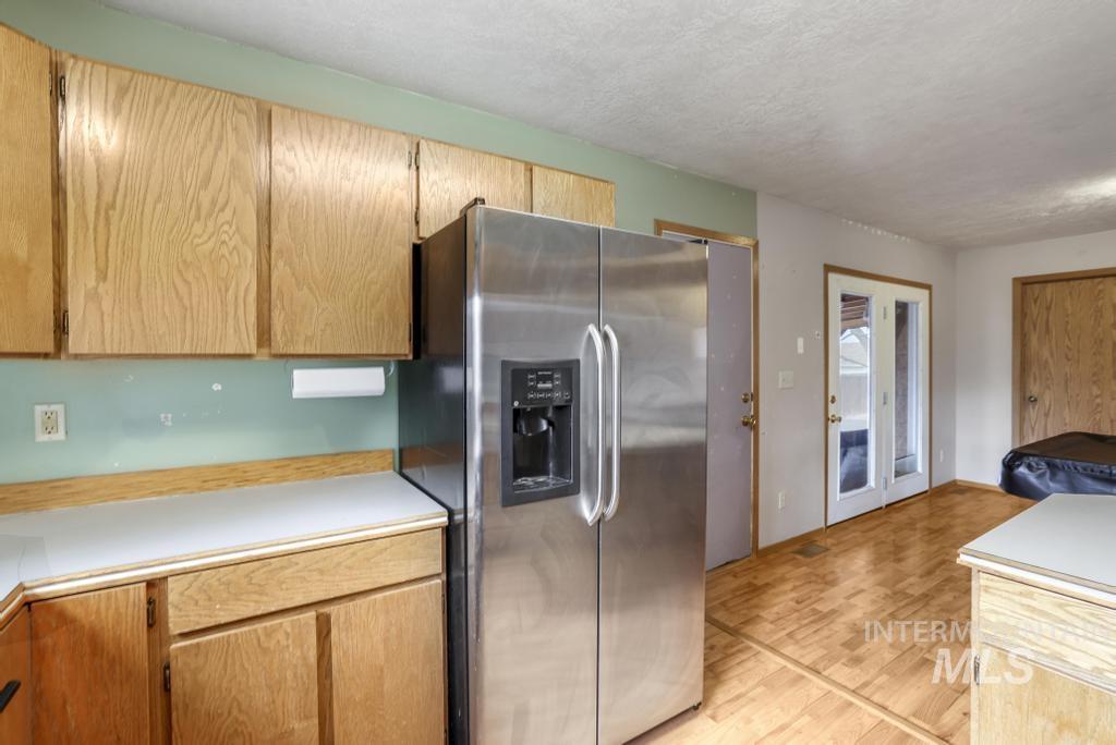 Kitchen with stainless steel fridge with ice dispenser, light countertops, a textured ceiling, light wood-type flooring, and light brown cabinetry