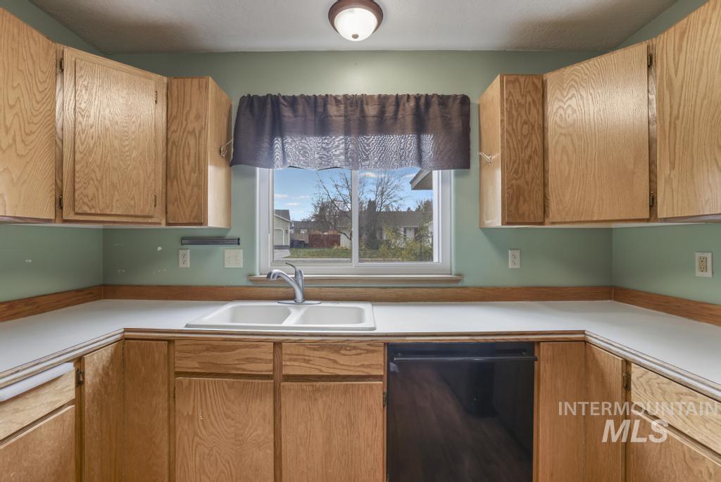 Kitchen with light countertops, dishwasher, and brown cabinets