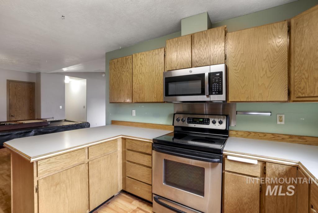 Kitchen featuring stainless steel appliances, a peninsula, light countertops, and a textured ceiling