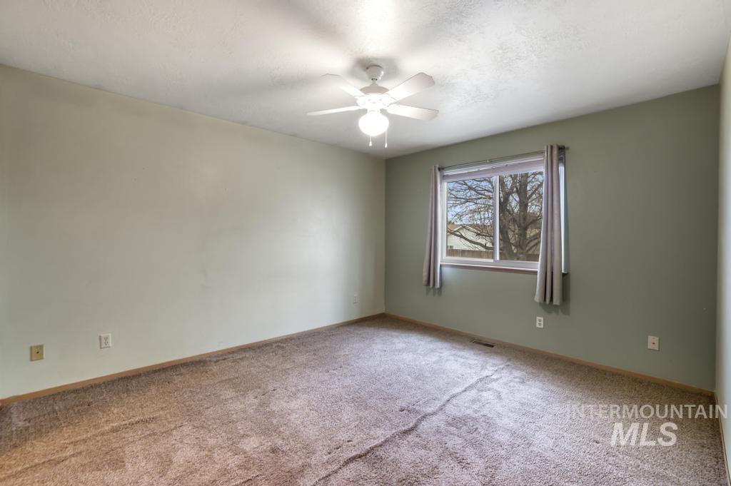 Empty room featuring ceiling fan, carpet flooring, and a textured ceiling