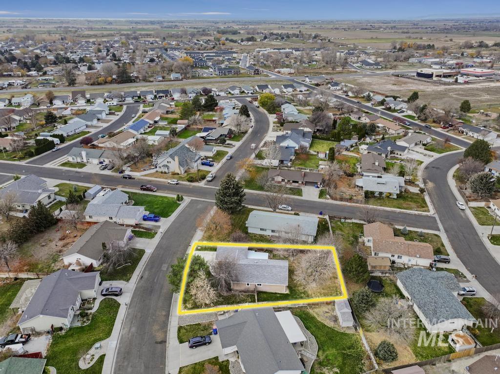Aerial view of property and surrounding area with property parcel outlined and nearby suburban area