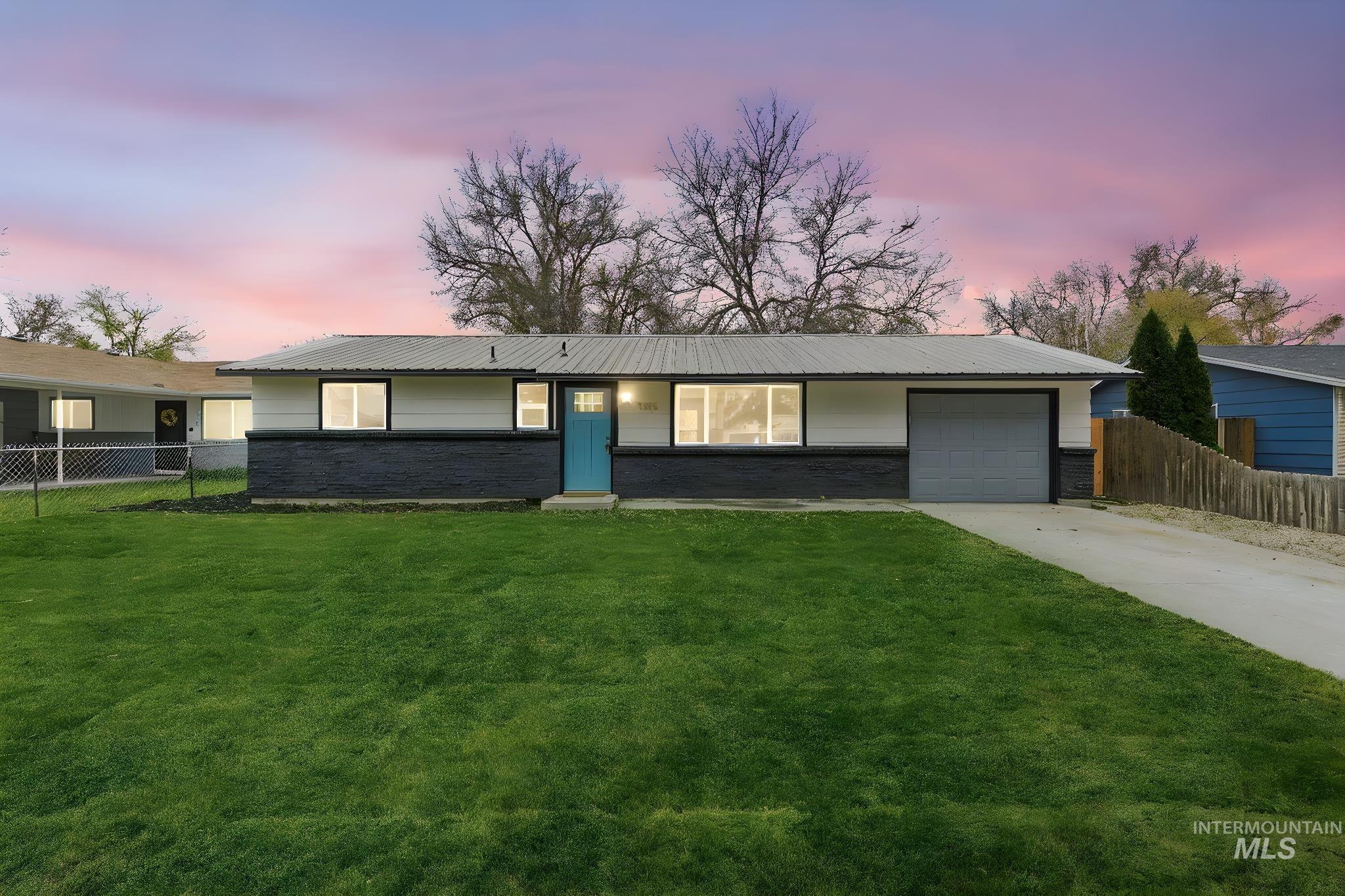 Ranch-style house with concrete driveway, a metal roof, a garage, and brick siding