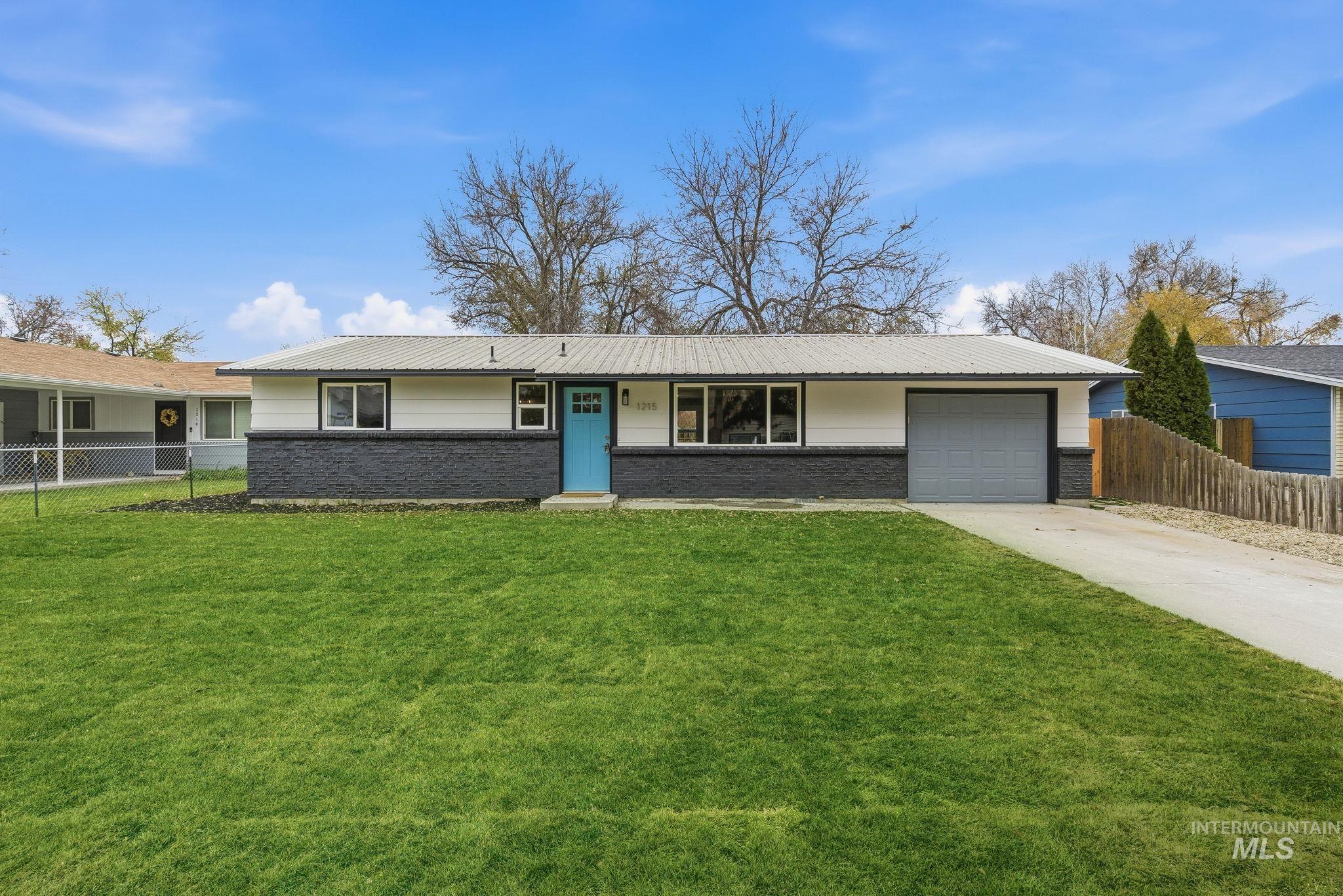 Single story home featuring brick siding, concrete driveway, an attached garage, and a metal roof